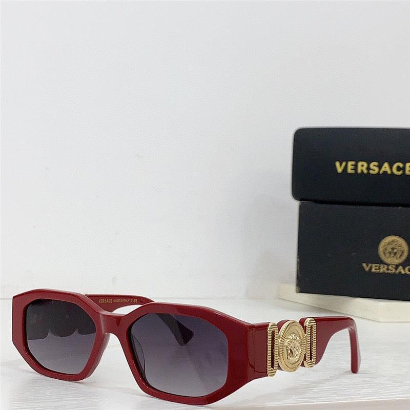 Red square sunglasses with gold side detail and dark lenses on white surface