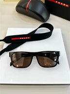 Rectangular black sunglasses with brown lenses and branded accessories on a white surface