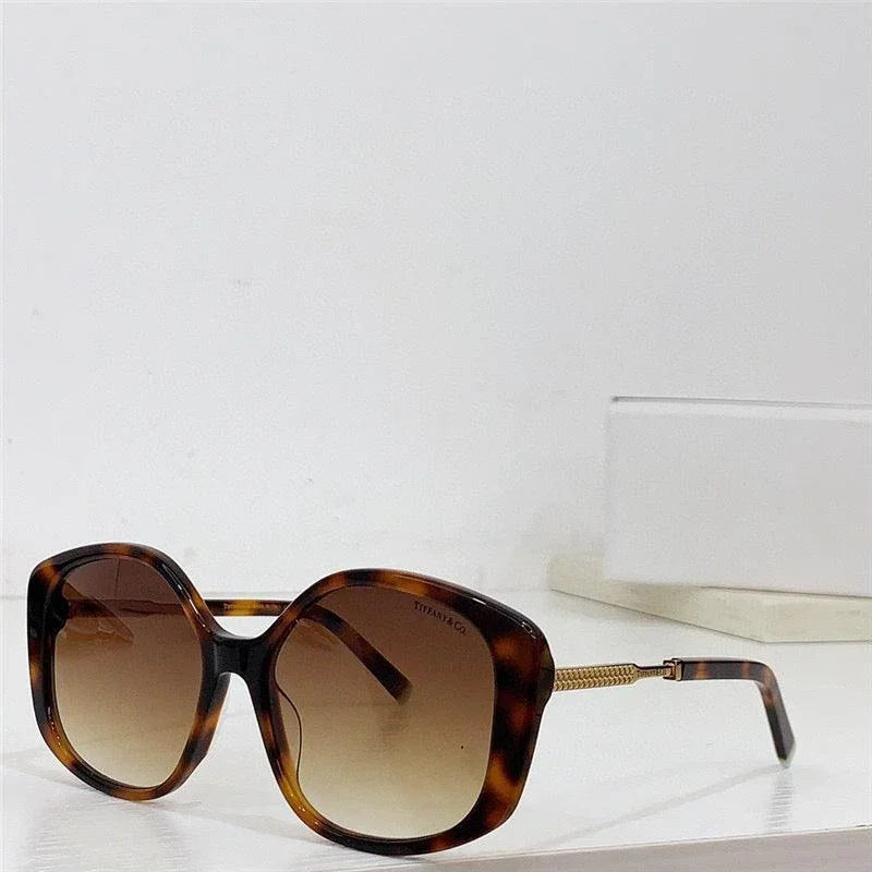 Tortoiseshell oversized sunglasses with gradient brown lenses and gold temple detail on white surface