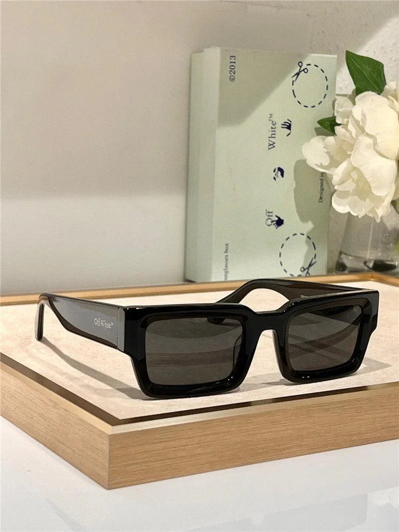 Black rectangle sunglasses with thick frame and dark lenses on a display tray