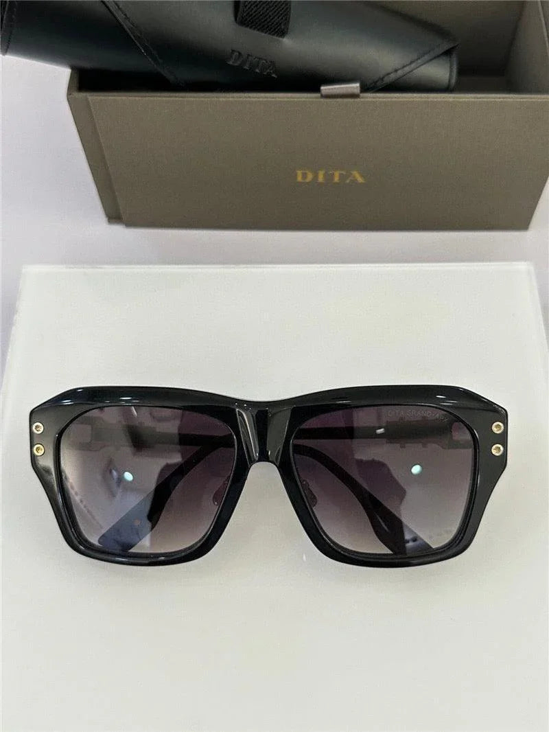 Black square sunglasses with dark lenses and gold accents, luxury eyewear on display.