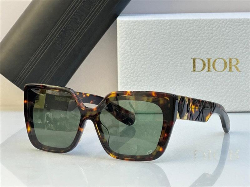 Tortoiseshell square sunglasses with green lenses displayed in front of branded packaging.