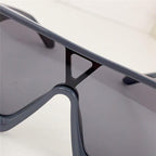 Close-up of oversized visor sunglasses with black frames and dark lenses