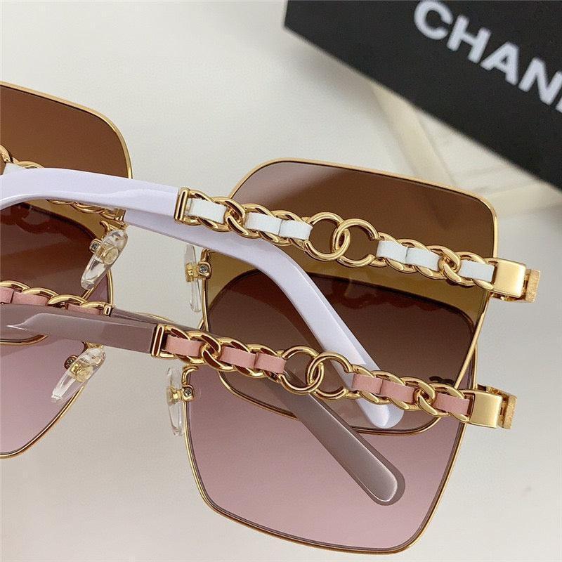 Square oversized sunglasses with gold chain arms, tinted lenses, and white or pink accents