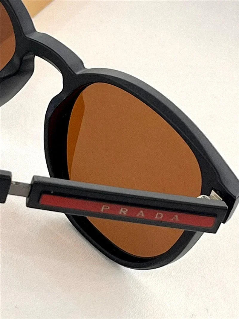 Close-up of black sunglasses with brown lenses and Prada logo on the temple.