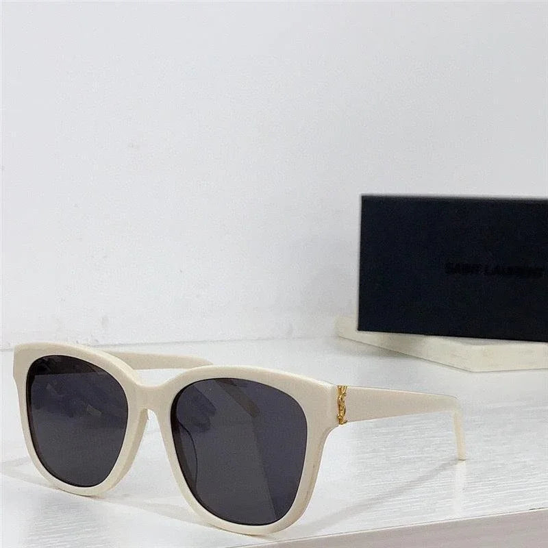 White square sunglasses with dark lenses and gold accent on the arms on a white surface