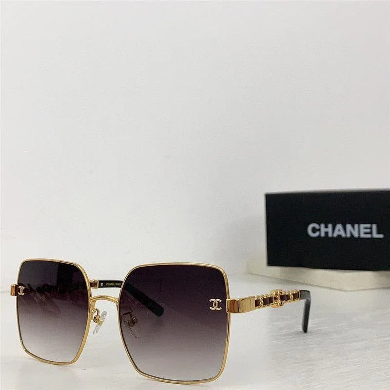 Gold square sunglasses with gradient lenses, designer logo detail, and black case in background
