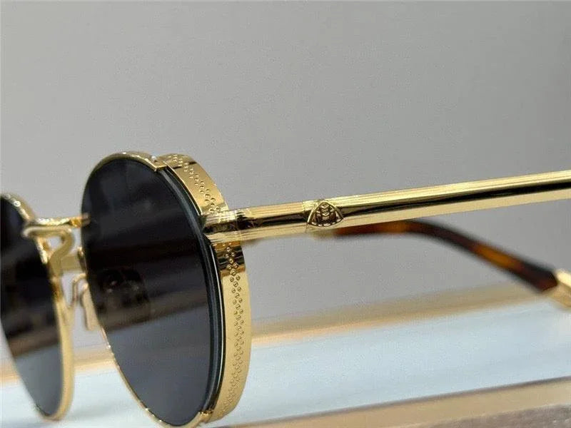Round gold metal sunglasses with black lenses and detailed frame close-up