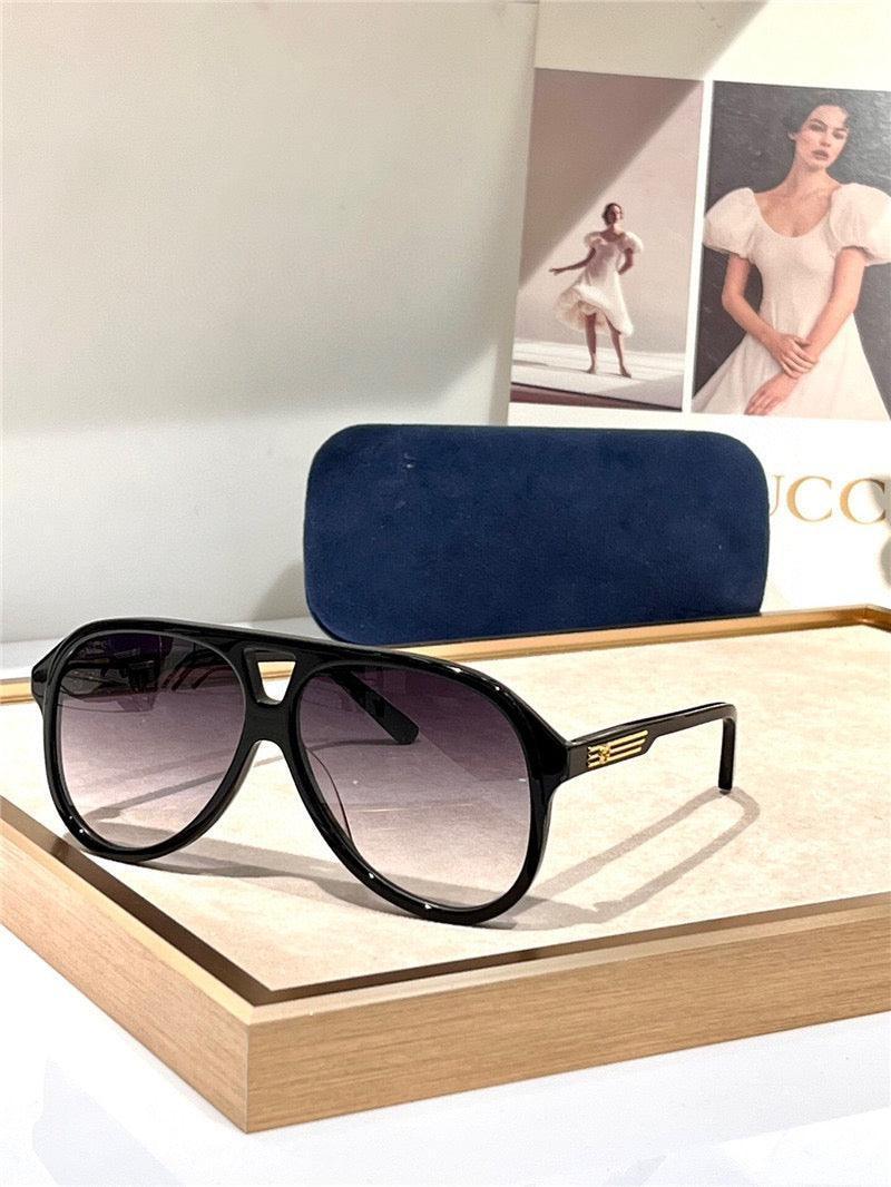 Black aviator sunglasses with gradient lenses, gold accents, and a blue case on display