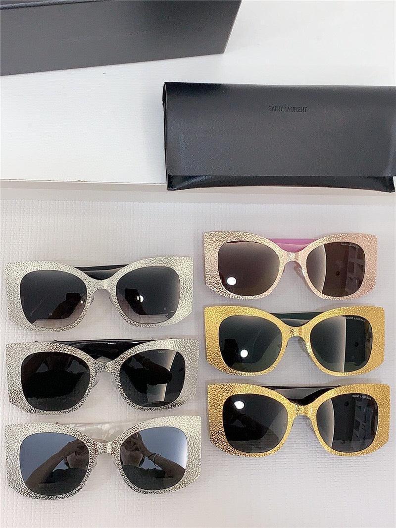Six pairs of oversized glitter sunglasses with black lenses in silver, gold, and rose gold frames, displayed with a black case.