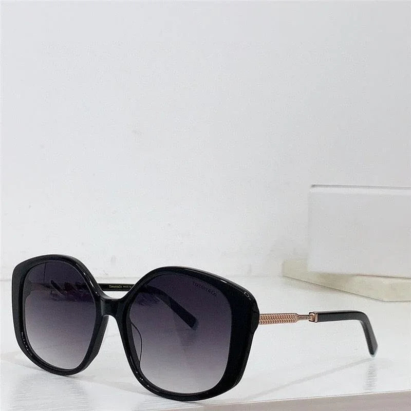Oversized black square sunglasses with gradient lenses and gold temple detailing on a white surface