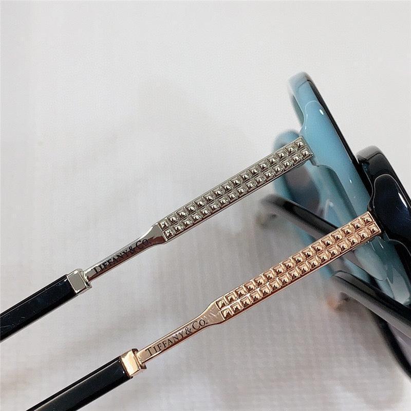 Close-up of luxury sunglasses with gold and silver studded arms and blue gradient frames