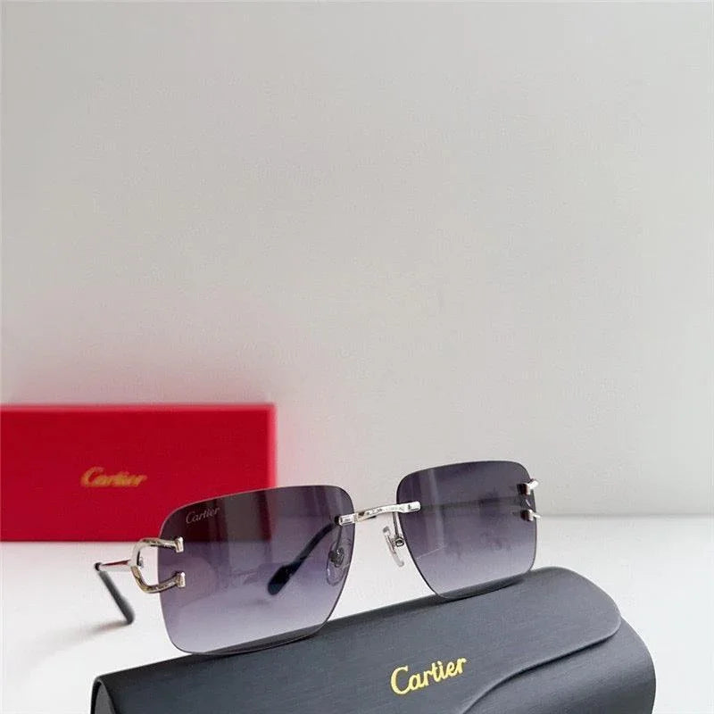 Rimless sunglasses with gradient dark lenses and silver temples, displayed with branded case and box
