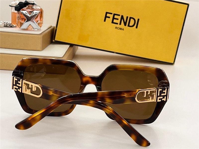 Tortoiseshell square sunglasses with gold accents and brown lenses, luxury packaging in background.