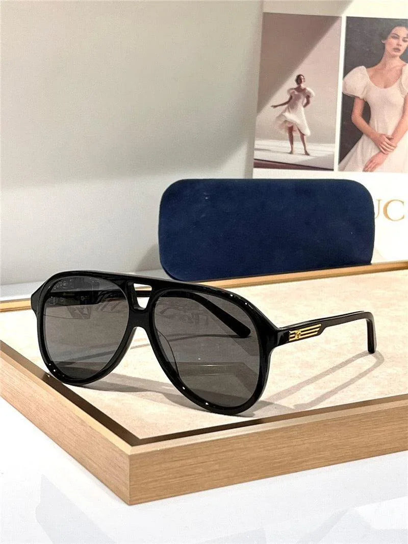 Black aviator sunglasses with dark lenses and gold accents on display tray