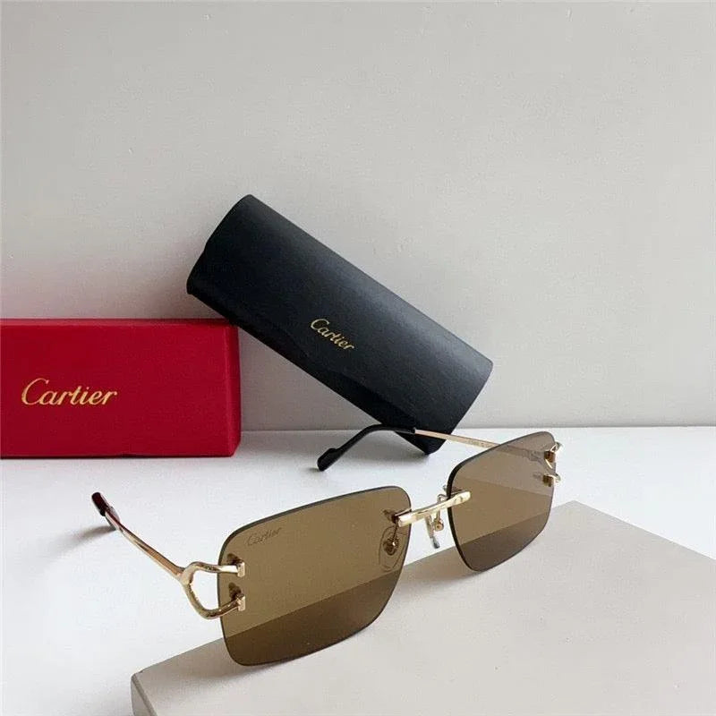 Rimless brown sunglasses with gold arms, black case, and red box on a white surface.
