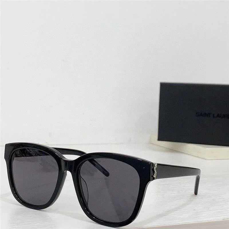 Black square sunglasses with dark lenses on white table, stylish premium eyewear close-up