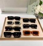 Display of trendy rectangular sunglasses in assorted colors and thick frames on a tray.