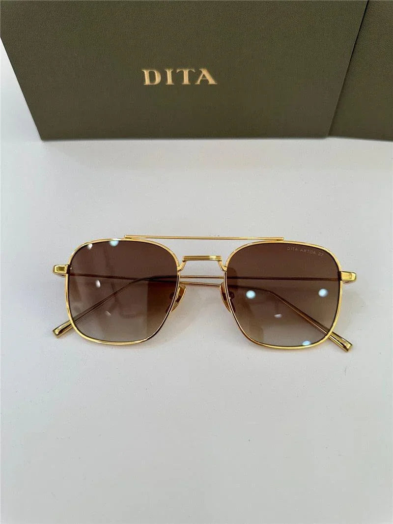 Gold frame sunglasses with brown square lenses, displayed on white surface with branded case