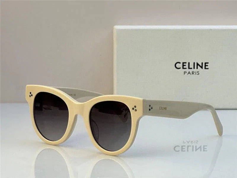 Beige designer sunglasses with round black lenses and thick frames, set on white surface