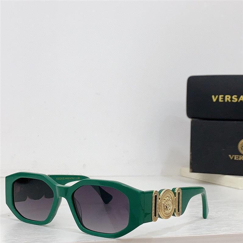 Green square-frame sunglasses with gold decorative accents and dark lenses on white surface