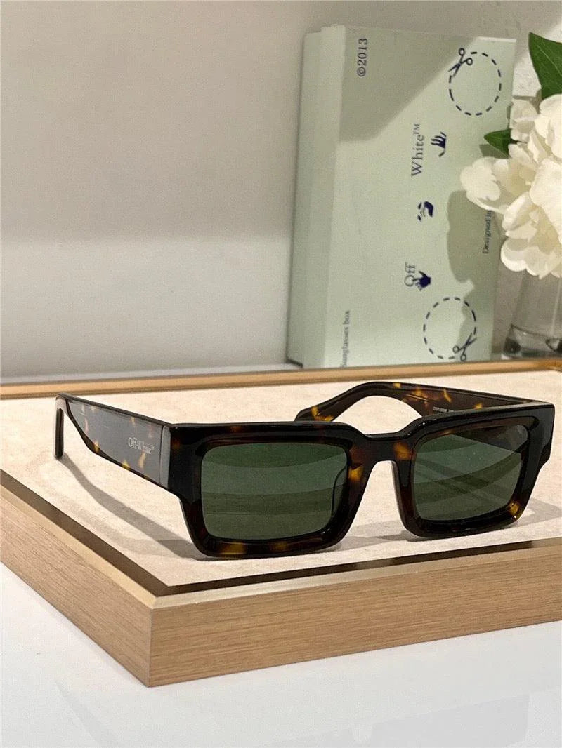 Tortoiseshell rectangular sunglasses with green polarized lenses on wooden tray