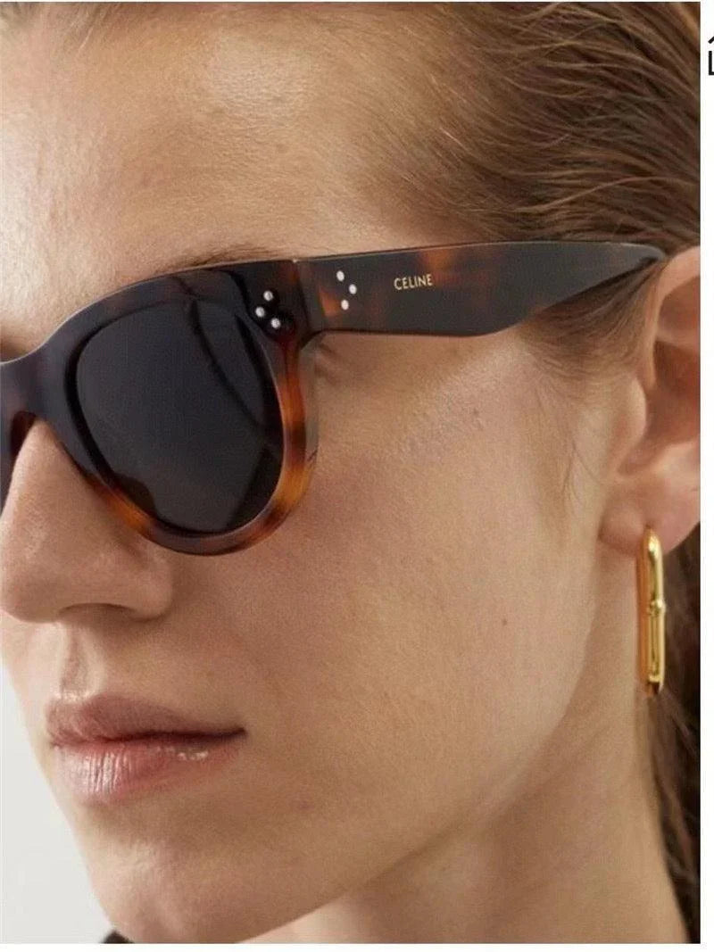 Woman wearing tortoiseshell Celine sunglasses and gold hoop earring, close-up