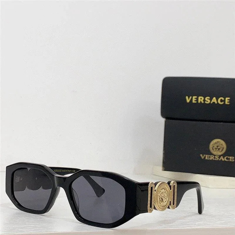 Black luxury sunglasses with gold accents and dark lenses, designer box in background