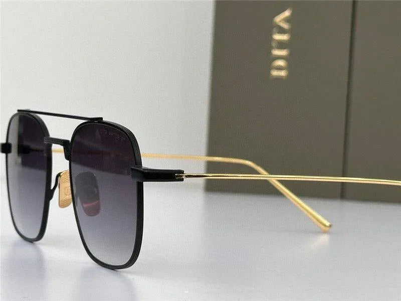 Black square sunglasses with gold metal arms and gradient lenses on a white background