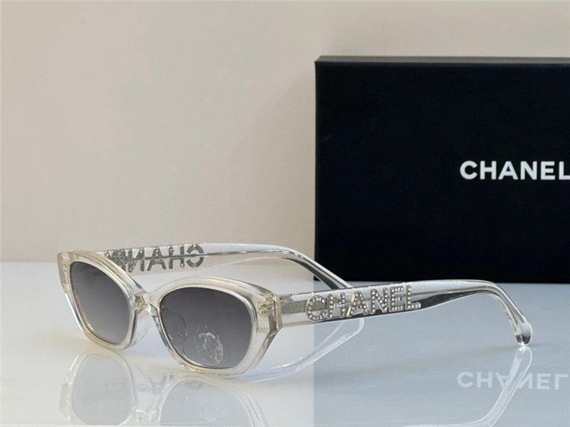 Clear frame sunglasses with gray gradient lenses and rhinestone logo on arms, boxed packaging