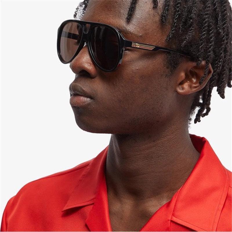 Man wearing oversized black sunglasses with dark lenses and a red collared shirt