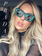Woman wearing bold green cat-eye Prada sunglasses with long blonde hair, inside a car.