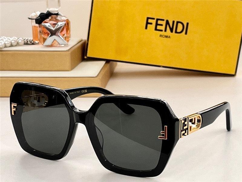 Black Fendi oversized square sunglasses with gold logo accents, set on a tabletop