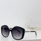 Oversized square sunglasses with gradient lenses and black and turquoise frames on a white surface