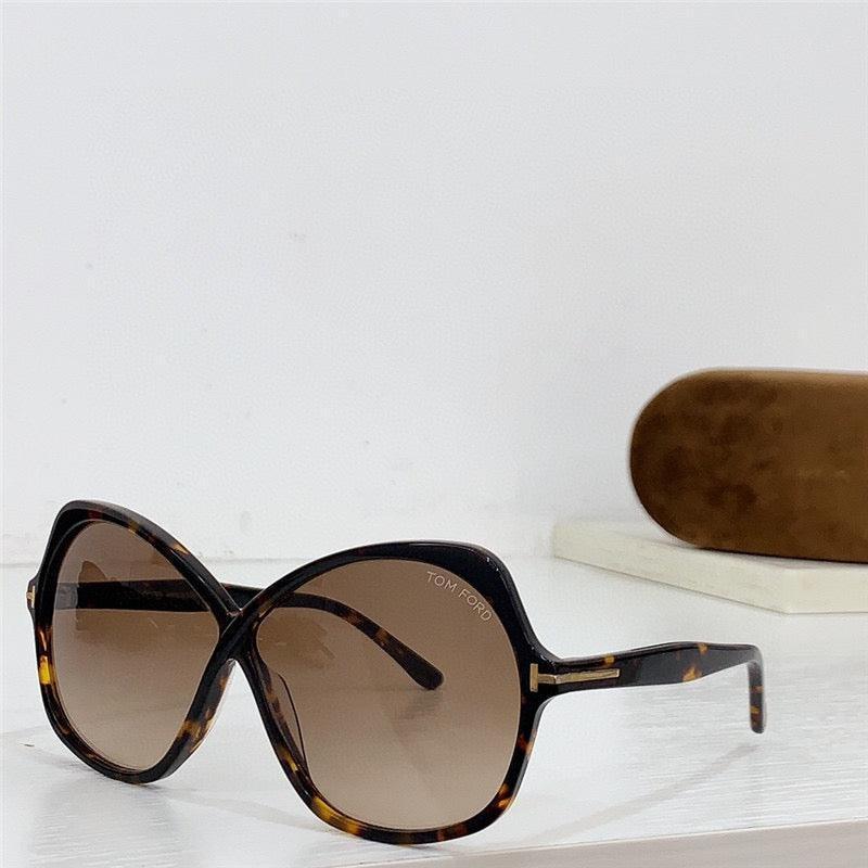 Oversized tortoiseshell sunglasses with brown gradient lenses and protective case on white table.