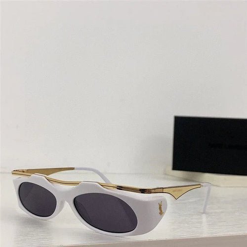 White and gold cat-eye sunglasses with dark lenses displayed on a white surface