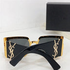 Black square sunglasses with gold logo detail and dark lenses, placed on white surface