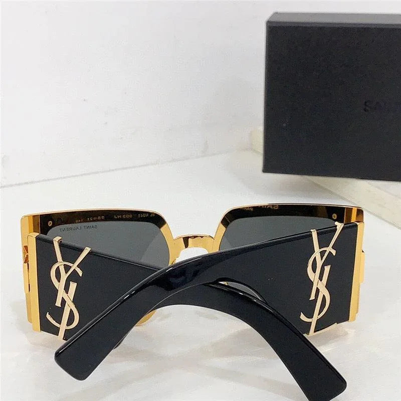 Black square sunglasses with gold logo detail and dark lenses, placed on white surface