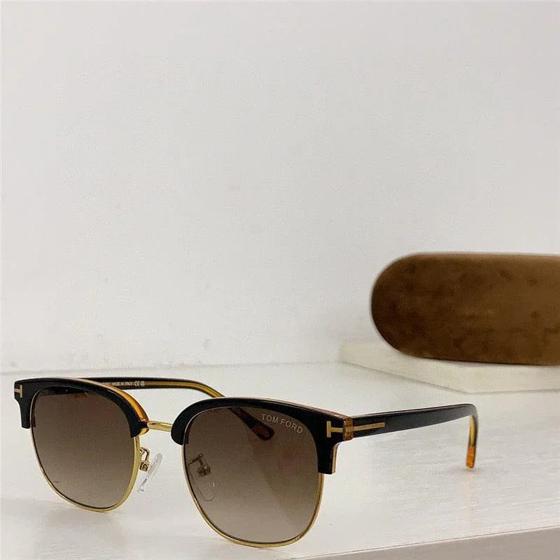 Classic black and gold sunglasses with brown gradient lenses and protective case on white surface