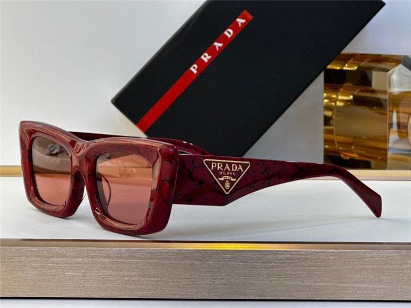Square oversized red sunglasses with marble pattern and gold trim, displayed by a case.