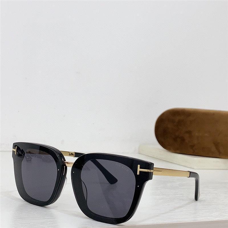 Black square sunglasses with gold arms and dark lenses on white table, sunglass case in background