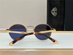 Gold round sunglasses with blue lenses and tortoiseshell arms on a display surface