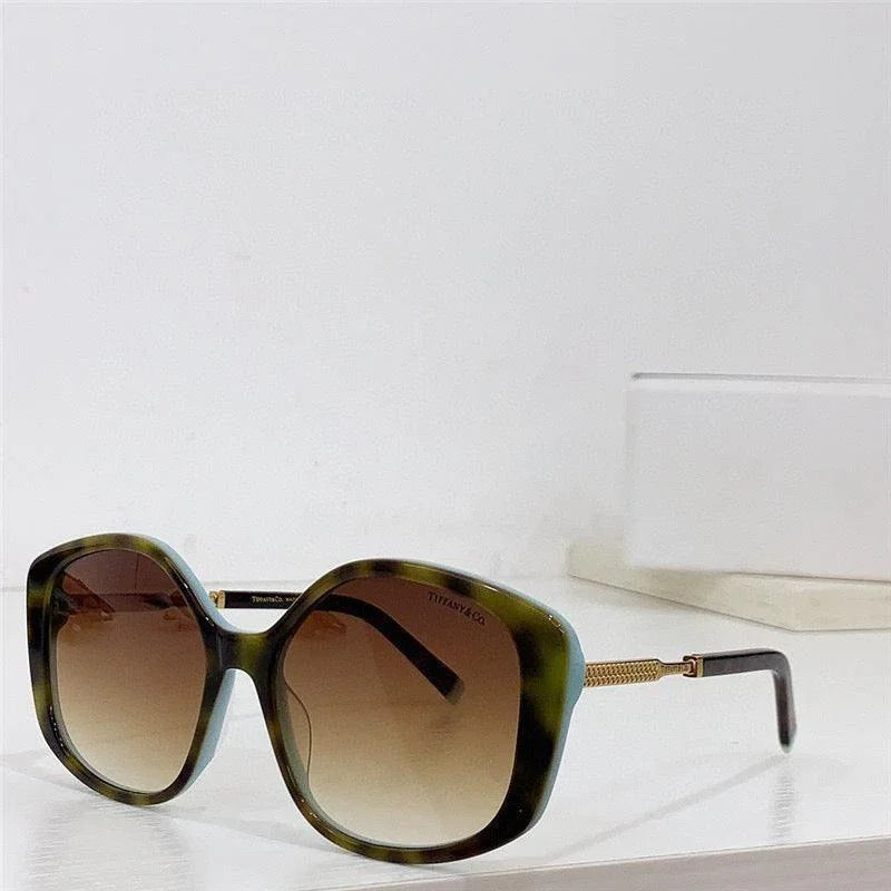 Oversized square sunglasses with green tortoiseshell frame and gradient brown lenses on table