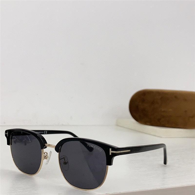 Black browline sunglasses with dark lenses and gold trim on a white surface, case in background
