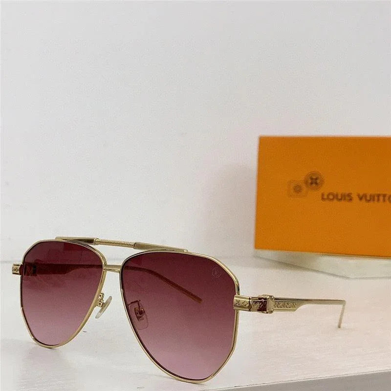 Gold frame sunglasses with pink gradient lenses on a white surface, designer eyewear box behind
