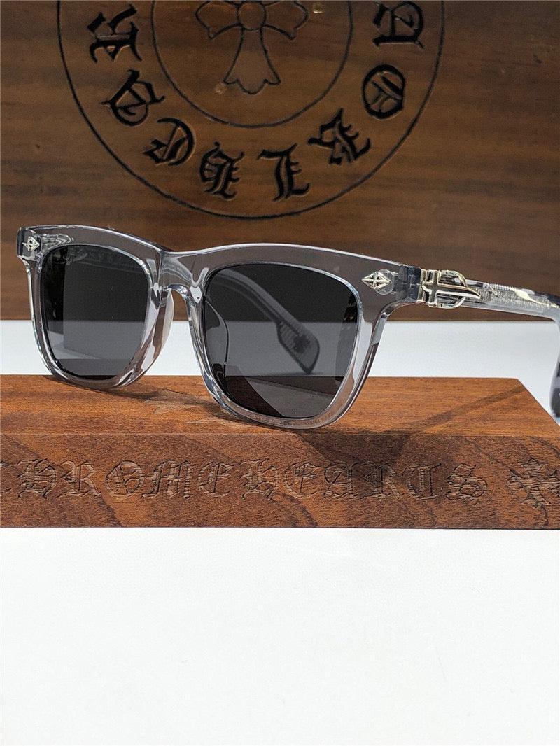Clear frame sunglasses with dark lenses and silver temple accents on a wooden display