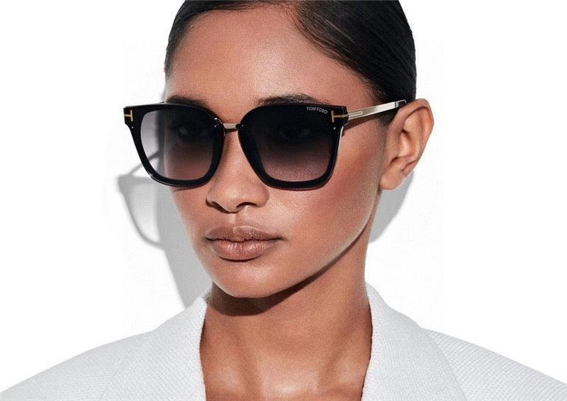 Woman wearing oversized square black sunglasses with gradient lenses and gold accents