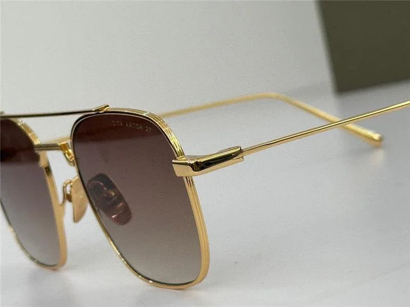 Gold frame sunglasses with brown tinted lenses on white background, stylish eyewear