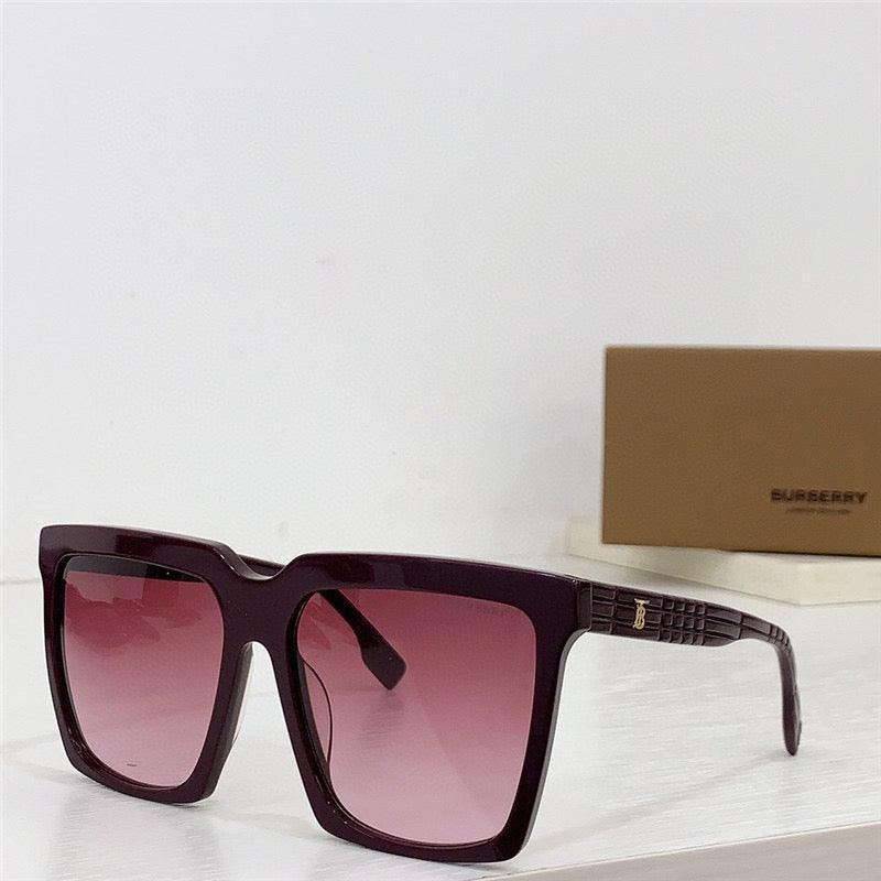 Oversized square sunglasses with burgundy frames and gradient pink lenses on white table