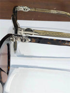 Close-up of luxury sunglasses arms with silver fleur-de-lis accents and tortoise frames.